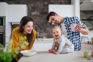 Happy Family Feeding Baby In Kitchen